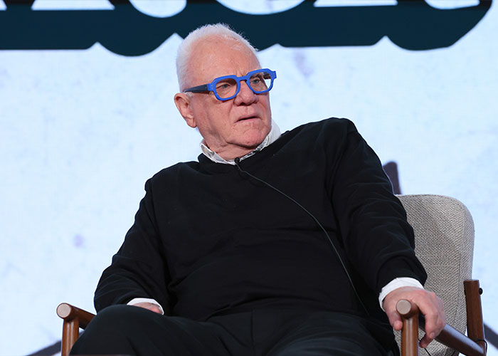 Older man with blue glasses and black sweater seated, speaking at an event about Kristen Bell and Fox News religious podcast backlash. Older man with blue glasses and black sweater seated, speaking at an event about Kristen Bell and Fox News religious podcast backlash.