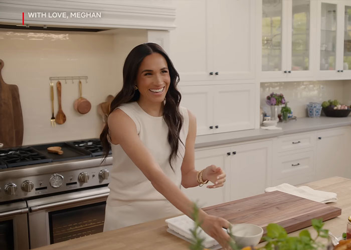 Meghan Markle smiling in a bright kitchen during her Harper&rsquo;s Bazaar moment sparking viral internet reactions.