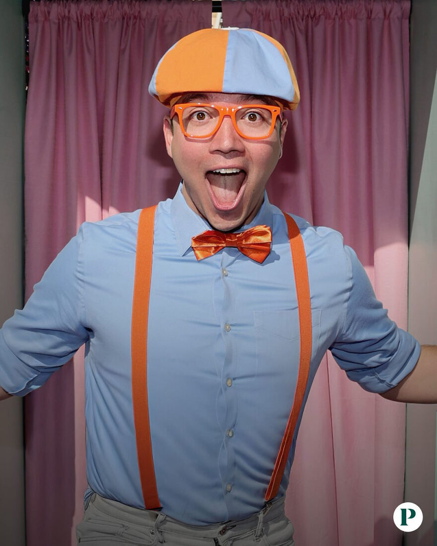 Actor Clayton Grimm dressed as Blippi wearing orange bow tie, suspenders, and hat, smiling enthusiastically in front of pink curtains.