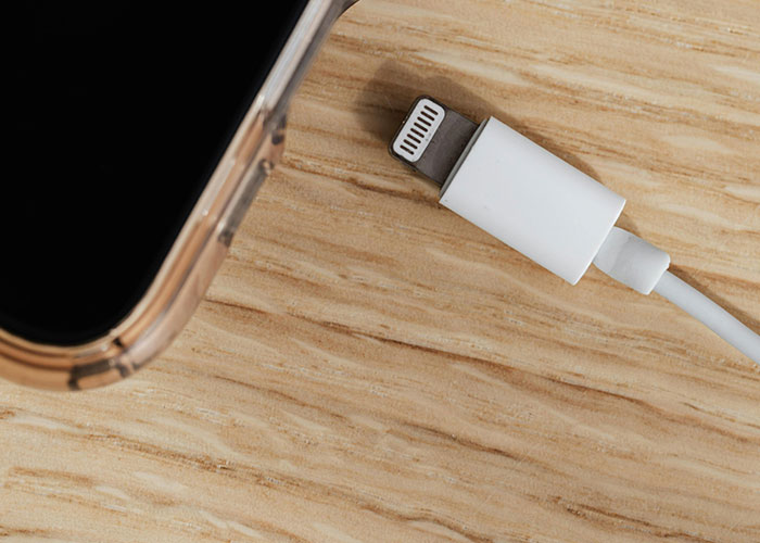 Smartphone with charging cable on wooden surface representing life hacks people share for daily convenience.