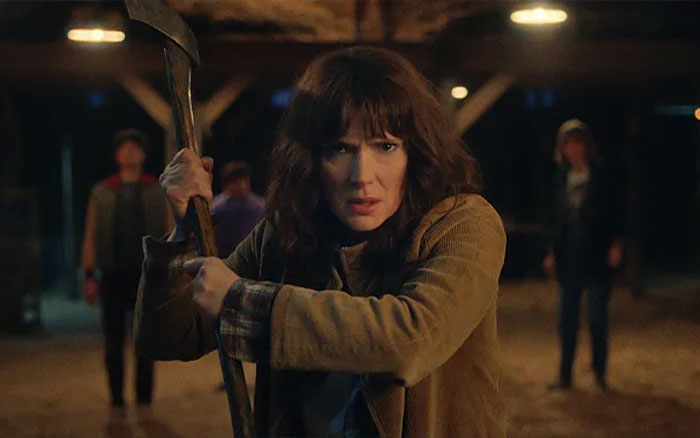 Woman in a tense stance holding an axe, representing Stranger Things creators' cryptic warning before final episodes.