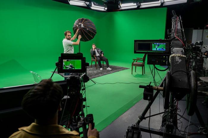 Film crew shooting in a studio with green screen backdrop, illustrating why modern movies look millennial gray and visually dull.