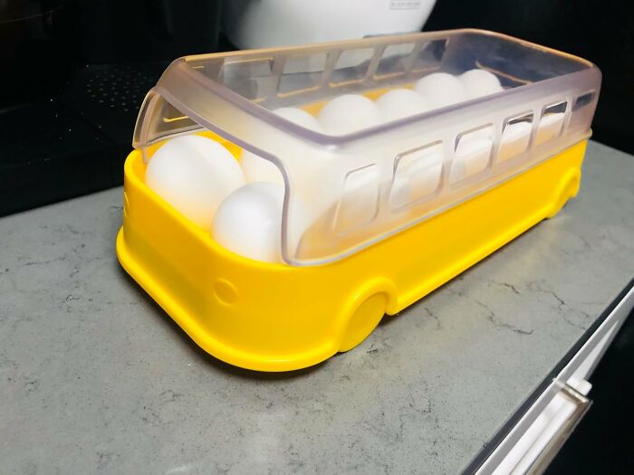 Yellow bus-shaped container holding white eggs on a gray kitchen countertop, a unique novelty find.