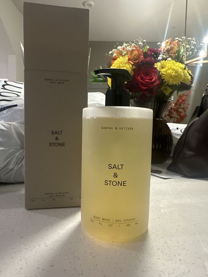 Salt and Stone body wash bottle and packaging on a counter with flowers in the background for Black Friday Week deals.
