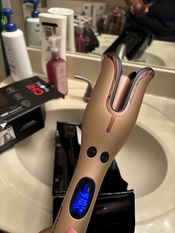 Rose gold automatic hair curler held over bathroom sink, highlighting main character splurges of Black Friday week.
