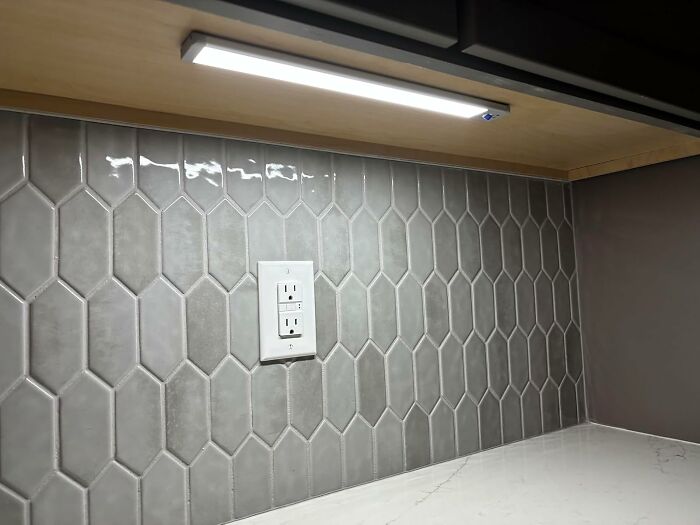 Kitchen backsplash with gray hexagonal tiles, white electrical outlet, and under-cabinet lighting showcasing 11.11 deals.