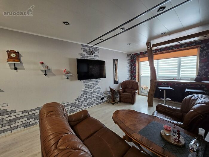 Living room with brown leather sofas and a wooden table, featuring wild real estate listings interior design ideas.