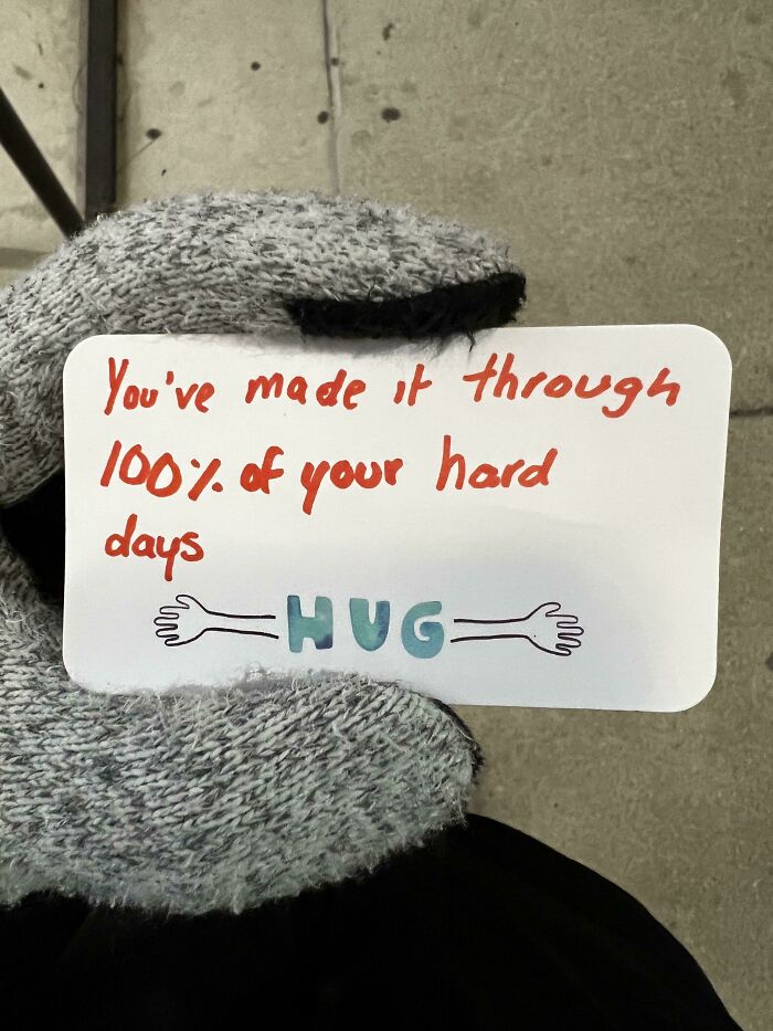 Hand in glove holding a card with encouraging message, showing faith in humanity restored through kindness.
