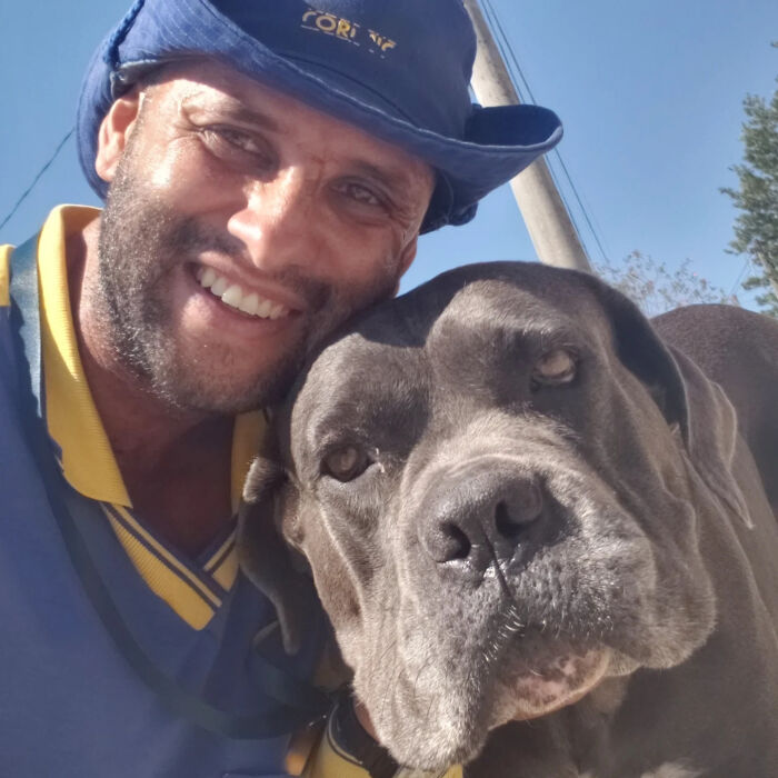 Mailman smiling with a large dog, showing their close friendship during his daily dog-friendly delivery route.