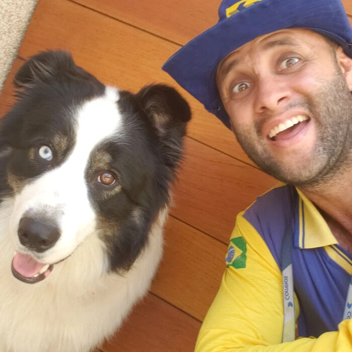 Mailman smiling with a friendly mixed-breed dog showing bond between mail carrier and dogs on his route.