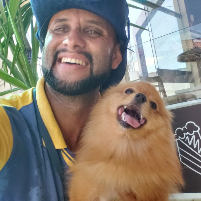 Mailman smiling and holding a happy fluffy dog, showing the bond between the mailman and dogs on his route.