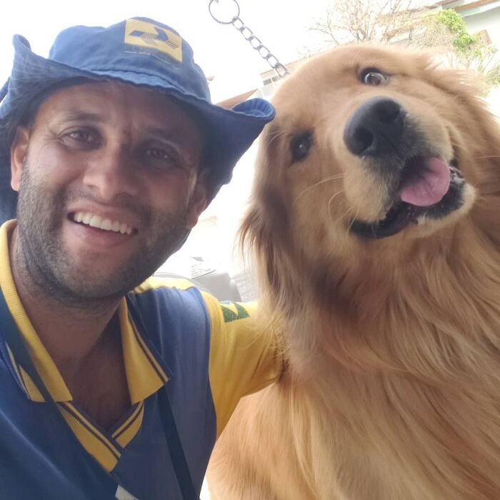 Mailman smiling next to a happy golden retriever, showing friendship with dogs on his delivery route.