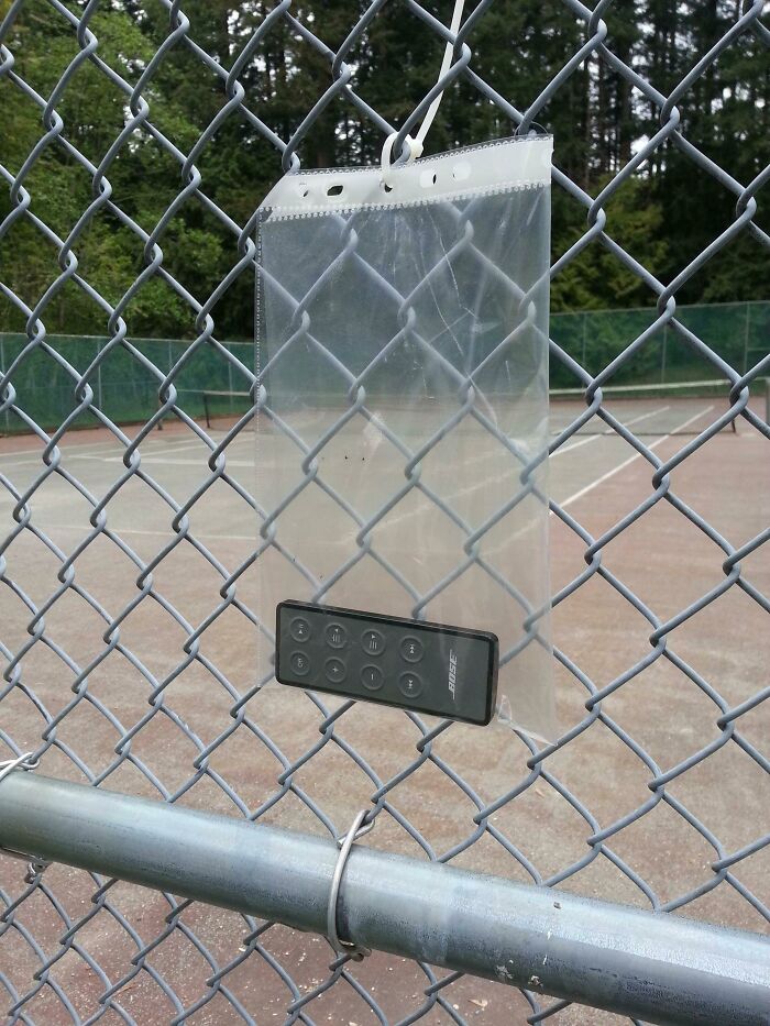 Small Bose remote hanging in a plastic sleeve on a chain-link fence showing faith in humanity restored kindness.