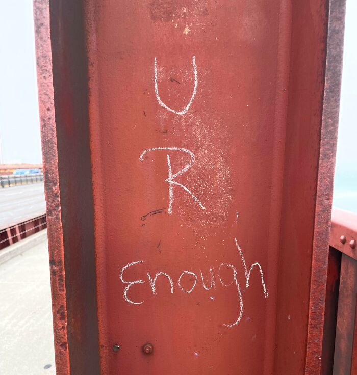 Chalk message saying U R Enough on a red metal beam, symbolizing faith in humanity restored and kindness from strangers.
