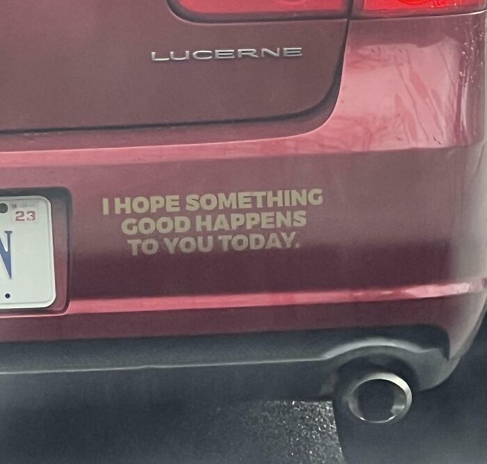 Positive message decal on back of red car, spreading faith in humanity and kindness to strangers.