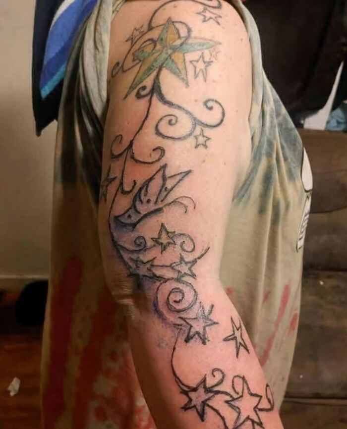 Arm tattoo with stars and swirls in black and green ink, an example of tattoos people allowed on their bodies.