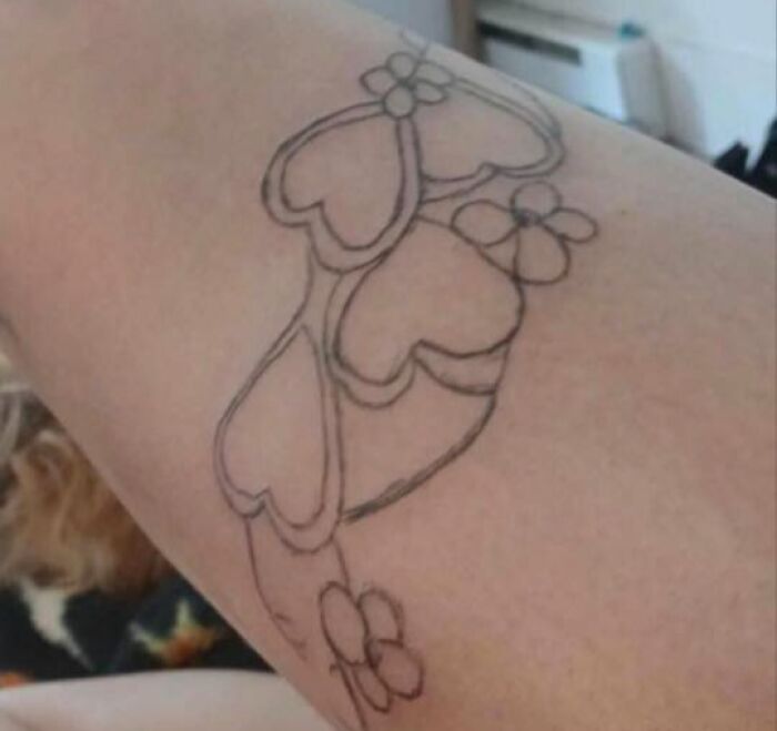 Outline tattoo of hearts and flowers on upper arm, one of the 91 tattoos you wouldn’t believe people allowed on their bodies.