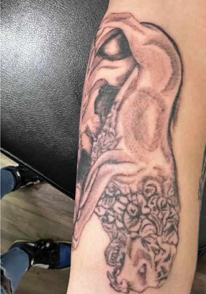 Tattoo of a distorted human face and figure on forearm, one of the unusual tattoos people allowed on their bodies.