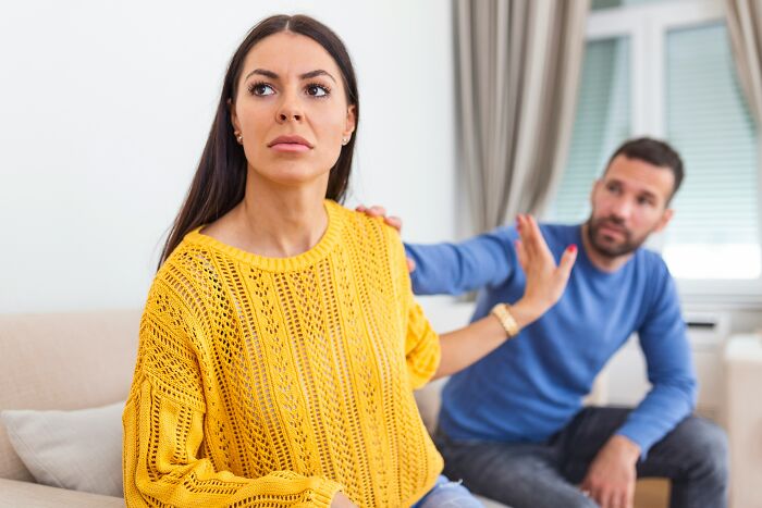 A woman in a yellow sweater rejecting a man’s touch, illustrating toxic relationship traits and emotional distance.