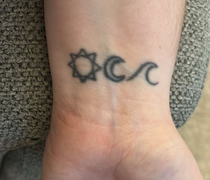Minimalist wrist tattoo featuring sun, moon, and wave symbols on a person's inner wrist, showcasing unique tattoo designs.