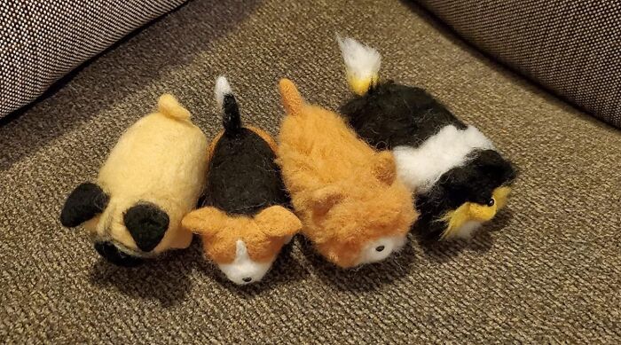 Four small felted wool animals lying on a brown fabric surface, showcasing a creative hobby for hibernation season.