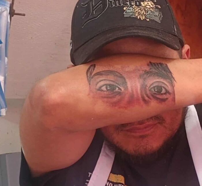Man with a realistic eye tattoo on his forearm covering his eyes, one of the 91 tattoos people allowed on their bodies for life.