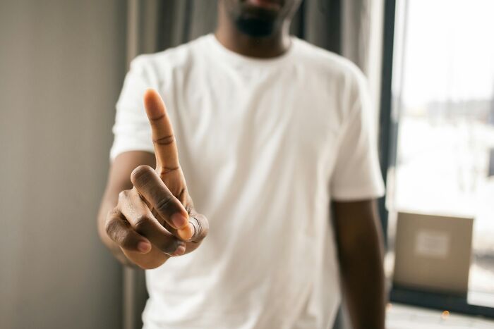 Man in white shirt pointing with one finger, representing toxic relationship traits to avoid in healthy connections.