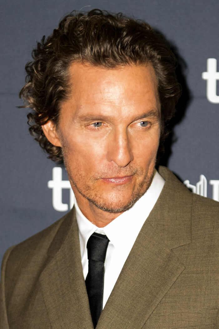 Matthew McConaughey wearing a brown suit and black tie at a formal event, highlighting his bio and career.