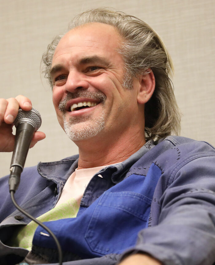 Steven Ogg smiling and speaking into a microphone during a casual interview or discussion session.