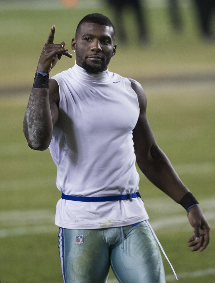 Dez Bryant on the field wearing a white sleeveless shirt and football pants during an NFL game.