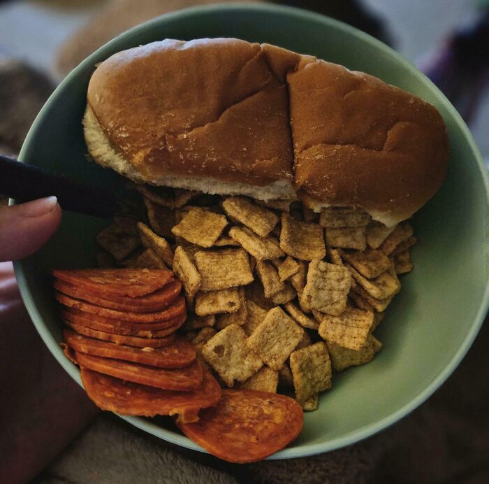 Bowl with warm dinner rolls, snack crackers, and sliced pepperoni showcasing iconic girl dinner combos.