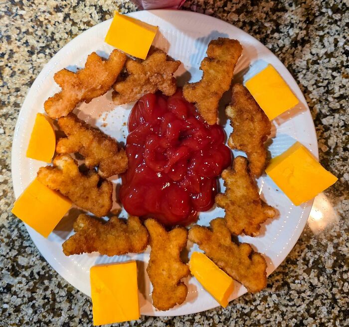Chicken nuggets and cheddar cheese slices arranged with ketchup in the center, a popular girl dinner combo.