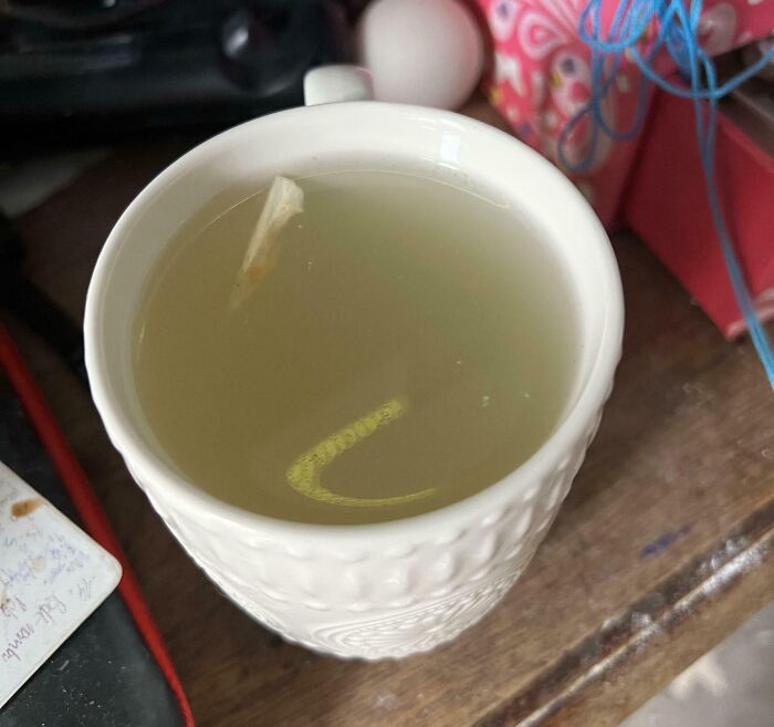 White mug filled with hot tea on a wooden table, part of popular girl dinner combos and cozy snack ideas.