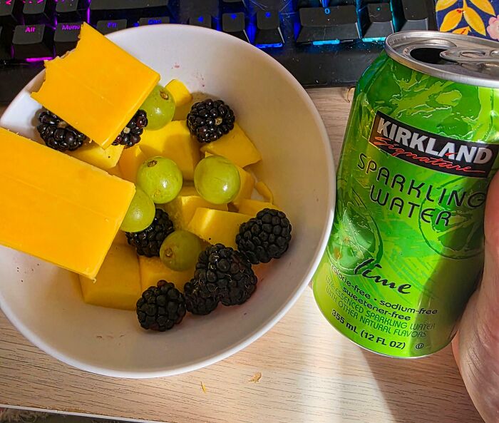 Bowl of blackberries, green grapes, mango chunks, cheddar cheese, and a can of lime sparkling water for girl dinner combos.