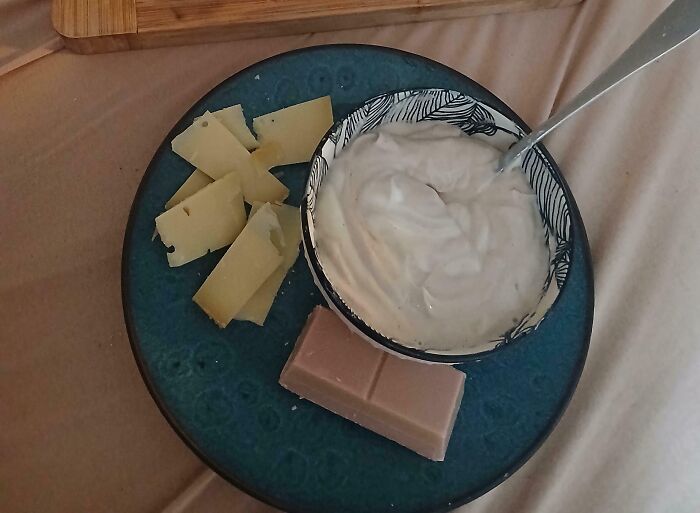 Plate with cheese slices, dip in a bowl, and chocolate square representing iconic girl dinner combos for girls.