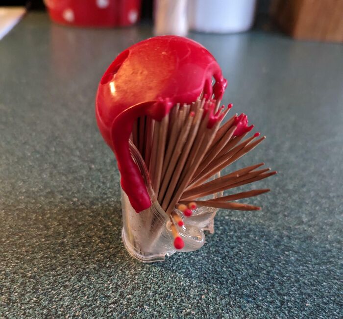 Toothpick holder covered in dripping red wax, showcasing a lack of common sense in everyday object use.
