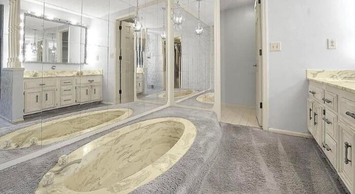 Bathroom of a unique Zillow home featuring a sunken tub, mirrored walls, and marble countertops in a spacious layout.