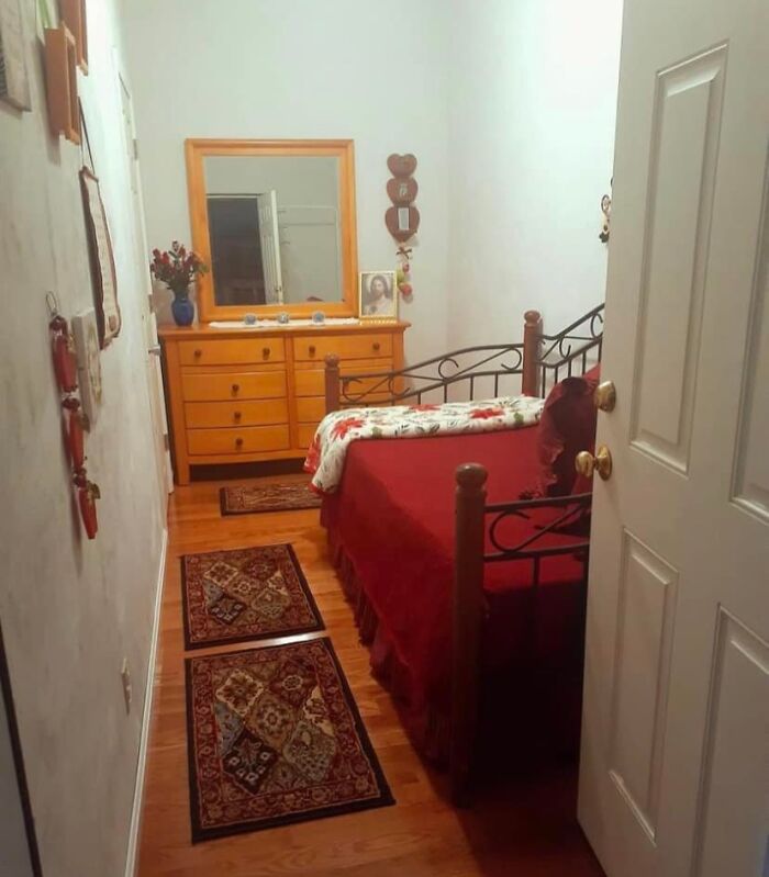 Cozy bedroom with wooden dresser and red bedspread in a Zillow home you have to see to believe.