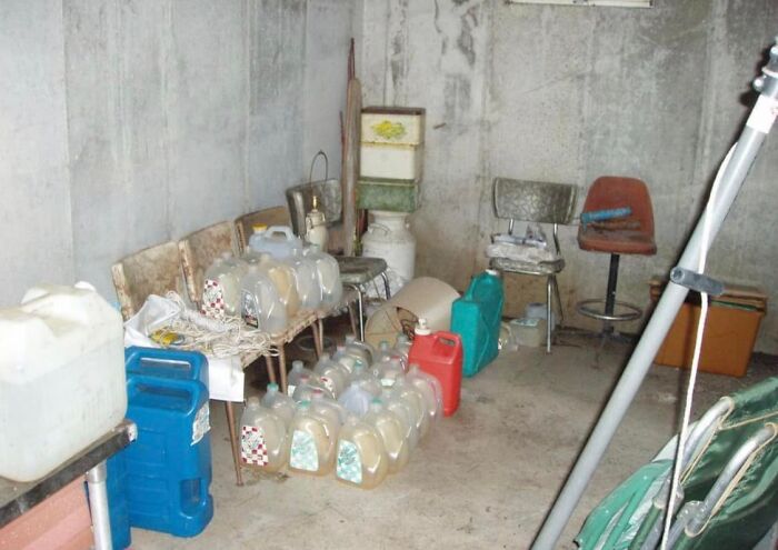 Cluttered basement storage with multiple plastic containers and old chairs in an unusual Zillow home setting.