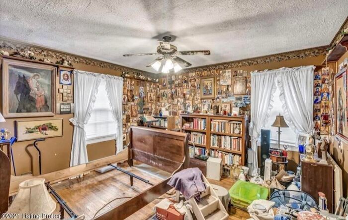 Cluttered Zillow home interior with vintage furniture, ceiling fan, and walls covered in numerous framed photos and artwork.