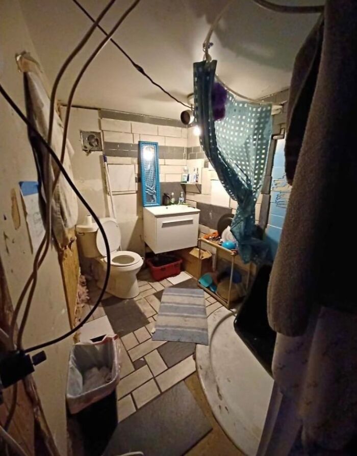 Unusual Zillow home bathroom with exposed wires, mismatched tiles, and eclectic shower setup in a quirky real estate listing.
