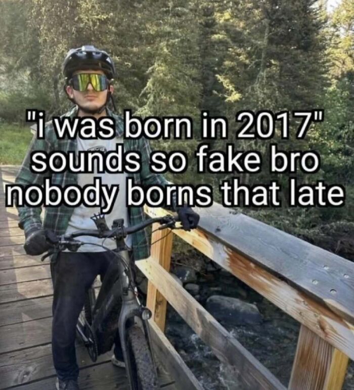 Man with bike on wooden bridge in forest with meme text about birth year, showcasing laughgorithm memes for a laugh today.