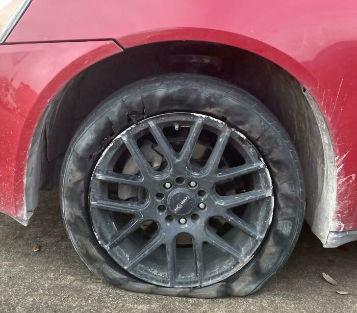 Flat tire on red car causing frustration, a relatable moment of family annoyance shared online for venting.