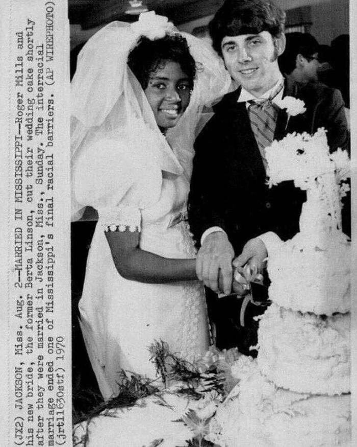 Interracial couple cutting wedding cake in Mississippi, a unique historical photo capturing a moment overcoming racial barriers in 1970.