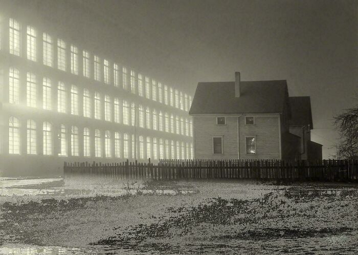 House surrounded by fog near a large illuminated historical building in an utterly unique historical photo scene.