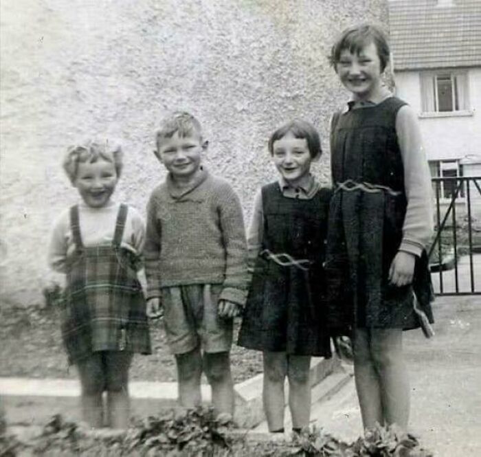 Four children smiling outdoors in a unique historical photo capturing a deep backstory from the past.