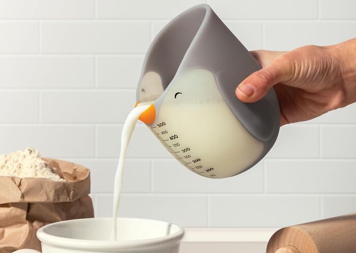 Measuring cup shaped like a penguin pouring milk into a bowl, one of the new kitchen finds trending now.