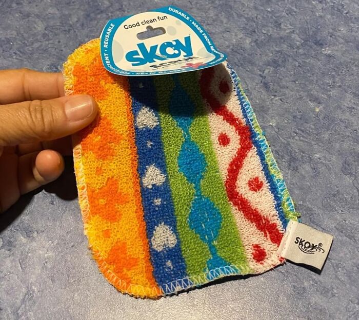 Hand holding a colorful reusable kitchen scrubber with patterns, a popular new kitchen find for cleaning tasks.