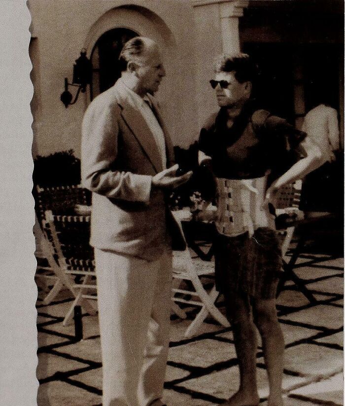 Two men engaged in conversation in a vintage setting, captured in a unique historical photo with deep backstory.