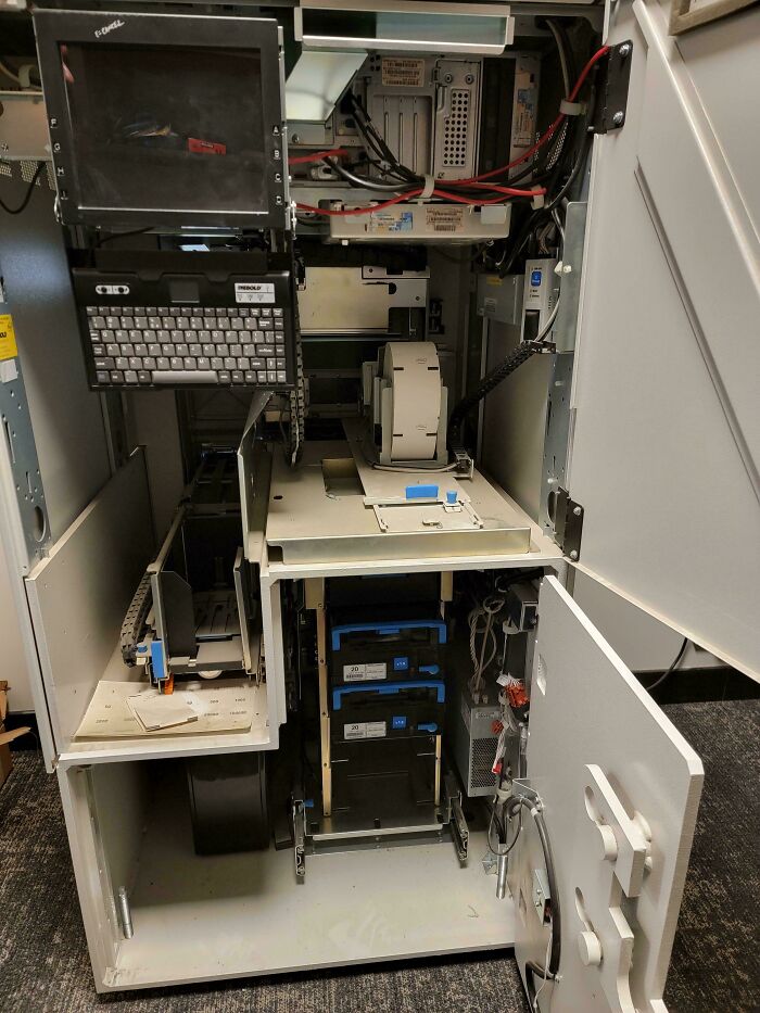 Open view of the inside components of an old ATM showcasing wiring, mechanical parts, and electronic modules.